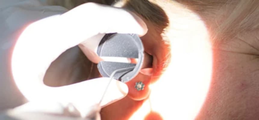 Ear under lighting having wax removed with specialized tool.